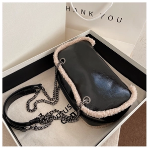 Detail of glossy black chain bag with beige faux fur trim in elegant gift packaging