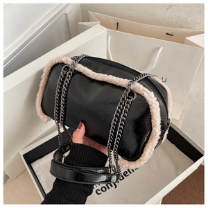 Detail of glossy black chain bag with beige faux fur trim and silver metal strap