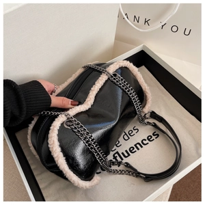 Close-up of gloss black leather cylinder bag with soft white faux fur trim and chain strap