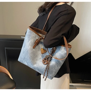 Détail du sac cabas en jean avec bandoulière en cuir marron et plaque logo vintage