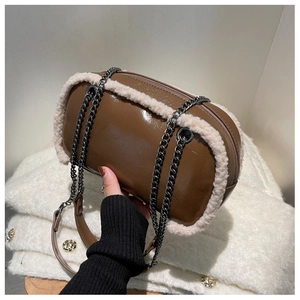 Close-up of brown patent leather chain bag with beige faux fur trim for winter