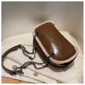 Detail of glossy brown bag with plush lamb wool trim and dark metal chain strap