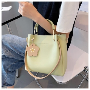 Detail einer hellgrünen Beuteltasche mit Metallgriff und Blumenanhänger am Modell