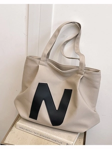 Large beige canvas tote bag with black leather N logo and wide shoulder strap