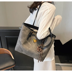 Détail du sac cabas gris montrant la texture brossée et l'écusson logo jaune distinctif