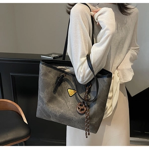 Détail du sac cabas gris foncé avec breloque bretzel et cordon à rayures