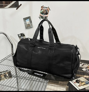 Vue détaillée du sac de voyage noir montrant la texture cuir et l'impression décorative