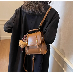 Detailed back view of a brown vintage mini backpack with gold studs and a plush bear charm