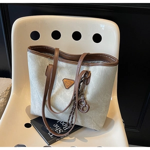 Détails du cabas rétro en toile avec finitions en cuir brun et logo métallique