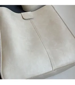 Detailed close-up of cream leather tote bag featuring visible texture and vertical stitching