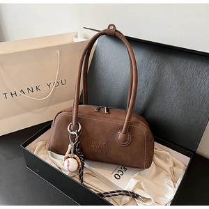 Close-up of brown litchi pattern leather handbag with logo and baseball pendant