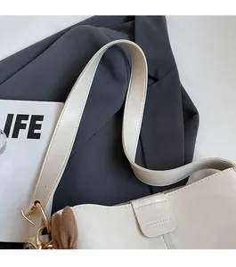 Close-up of cream leather tote bag with adjustable strap and decorative brown bow detail