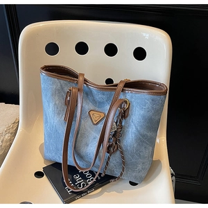 Vue détaillée du cabas en denim avec anses en cuir et plaque logo triangle