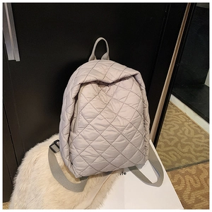 Détail du sac à dos matelassé gris clair avec coutures en losanges et fermeture éclair