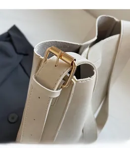 Detail of premium gold-toned metal buckle on a beige minimalist leather handbag