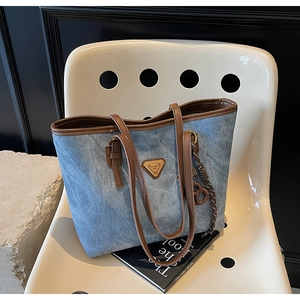 Détail du sac cabas vintage bleu avec des poignées en cuir marron et un logo triangle