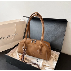 Close-up of brown litchi pattern leather bag inside a luxury black gift box with satin