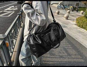 Détail d'un sac de voyage noir en cuir PU avec texte inspirant et bandoulière amovible