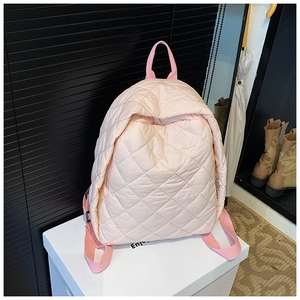 Détail d'un sac à dos matelassé rose clair avec texture satinée et coutures en losange