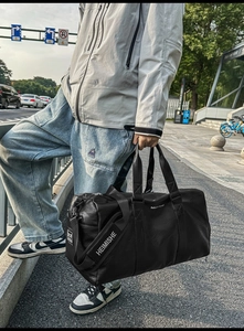 Détail du sac de voyage en cuir PU noir avec inscription et bandoulière large imprimée