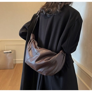 Detail view of large dark brown leather croissant bag showing texture and silver zipper