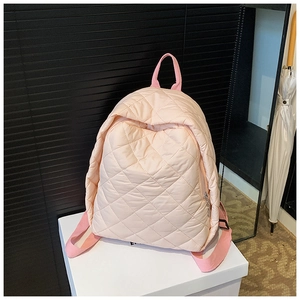 Gros plan d'un sac à dos matelassé rose montrant les losanges et le zip en métal