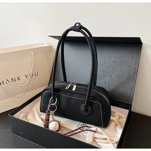 Close-up of black lychee texture bowling bag with baseball charm in a premium gift box