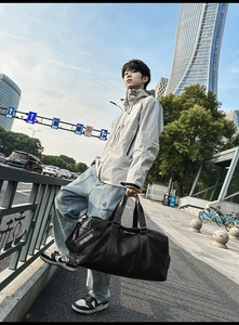 Vue détaillée du sac de voyage en cuir noir avec bandoulière large logo HEIMISHE
