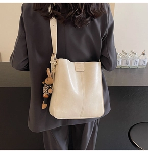 Detail view of beige matte leather bucket bag with cute brown rabbit plush charm accessory