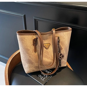 Détail du cabas vintage marron avec texture cuir mat et plaque métallique dorée