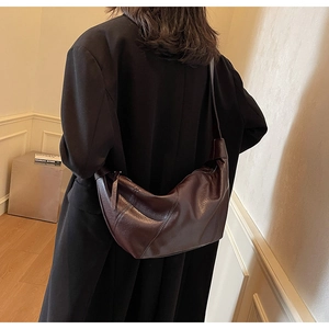Detail view of a vintage dark brown crescent bag worn with a black wool coat