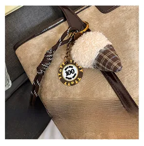 Détail de charme gland en peluche avec corde tressée sur un sac fourre-tout PU