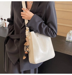Detail of cream minimalist tote bag with smooth texture and cute rabbit charm