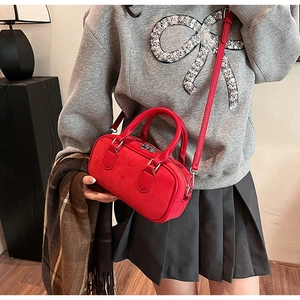 Red boston bag with textured finish shown on model with shoulder strap and handles
