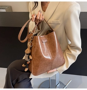 Close-up of retro brown bucket bag with rabbit charm and embossed leather details