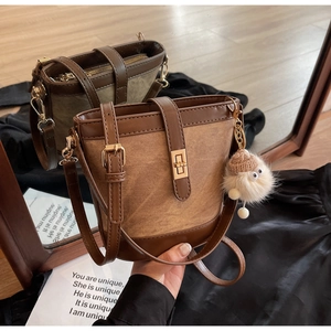 Detail view of retro bucket bags with metal turn-lock and plush charm on dark silk