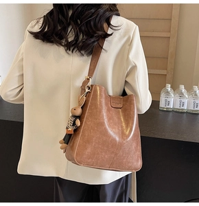 Detail shot of brown vintage bucket bag with rabbit charm and adjustable shoulder strap