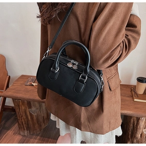 Detail of black Boston bag with silver hardware and dual zippers in cafe setting