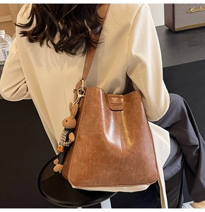 Detail of vintage brown bucket bag with stitched texture and cute rabbit plush charm
