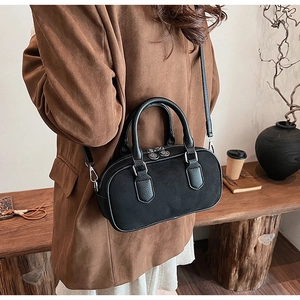 Detail of a black pebbled leather satchel bag styled on a model in a vintage setting