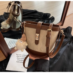 Close-up of beige canvas bucket bag with brown leather trim and golden metal lock