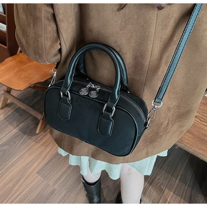 Close-up of black Boston bag with dual textures, leather handles and silver flower zipper