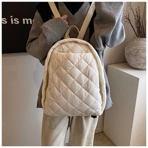 Détail du sac à dos matelassé crème avec finition brillante et bretelles en tissu