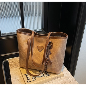 Détail d'un sac cabas marron vintage avec logo triangle en métal et similicuir