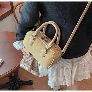 Macro view of beige Boston bag with silver double zippers and textured leather handles