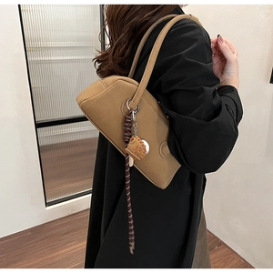 Detail of caramel pebbled leather bowling bag featuring a baseball glove charm