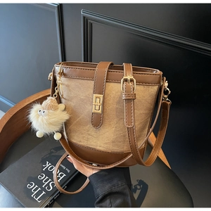 Detail view of contrast bucket bag with gold clasp and furry monster charm