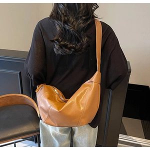 Rear view of a model wearing the brown matte leather dumpling bag with wide strap