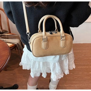 Close-up of beige leather crossbody bag with dual zipper and adjustable shoulder strap