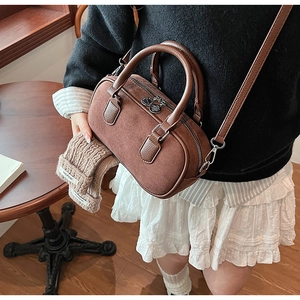 Detail of vintage brown suede Boston bag with textured leather handles and gold metal clips
